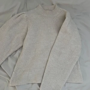 Beige stickad tröja från NLY Trend - Säljer en beige stickad tröja från NLY Trend i storlek S. Tröjan har hög hals och långa puffärmar. Tröjan är aldrig använd! 