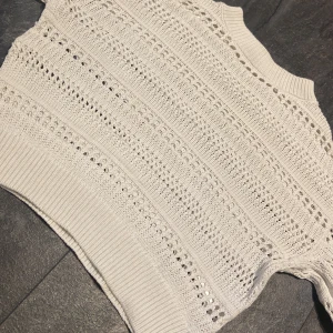 Vit stickad tröja från H&M - Säljer en vit stickad tröja från H&M med hålmönster och ribbade muddar. Tröjan har lång ärm och är perfekt för lager-på-lager. Snygg och enkel att matcha till olika outfits. Finns även några lite större hål men som knappt märks🥰