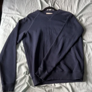 Mörkblå sweatshirt från Pier One - En stilren mörkblå sweatshirt från Pier One med rund halsringning och ribbade muddar vid ärmslut och nederkant. Perfekt för en avslappnad och enkel look. Klassisk passform och mjukt bomullsmaterial.