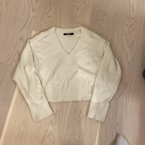 Vit croppad stickad tröja från Bik Bok - Säljer en vit croppad stickad tröja från Bik Bok med v-ringad hals och breda ribbade muddar. 
