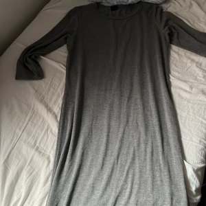 Grå långärmad klänning - En enkel och stilren grå långklänning med rund halsringning och långa ärmar. Tillverkad i mjukt och stretchigt material som känns bekvämt mot huden. Perfekt för dig som gillar minimalistisk stil.