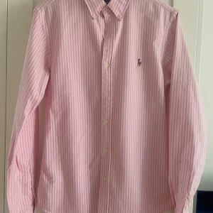 Rosa och vit randig skjorta från Polo Ralph Lauren - Säljer en rosa och vit randig skjorta från Polo Ralph Lauren i slim fit. Bra skick