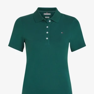 Grön pikétröja från Tommy Hilfiger - Klassisk grön pikétröja från Tommy Hilfiger med korta ärmar och knappslå framtill. Tröjan har en liten broderad logga på bröstet och är tillverkad i bomull. Perfekt för en avslappnad och sportig stil.                        Pris kan diskuteras!