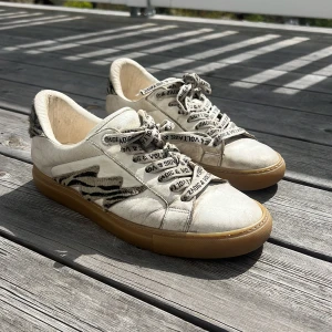 Zadig & Voltaire sneakers med zebramönster - Snygga vit/beigea sneakers från Zadig & Voltaire med zebramönstrade detaljer på sidan och hälen. Ord pris- 3000, mitt pris- 700