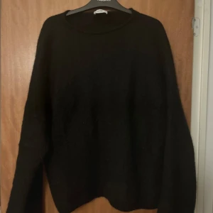 Svart stickad tröja - En enkel och stilren svart alpaca  tröja med rund halsringning och långa ärmar. Perfekt att matcha med jeans eller kjol för en avslappnad look. Strl xs-s