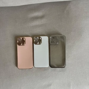 3-pack mobilskal i olika färger - Säljer tre snygga mobilskal till iPhone 13 PRO Max, då jag råka beställa fel storlek. Ett är rosa med gulddetaljer, ett är vitt med gulddetaljer och ett är transparent med silvrig kant. Alla har öppning för kamera och knappar på sidan. Perfekt för att variera stilen på mobilen. Helt oanvända! 1 för 40 alla för 100kr!