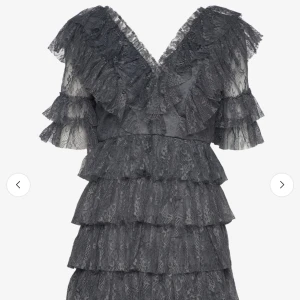 Grå klänning från By Malina - Supersnygg grå spetsklänning från By Malina med flera lager volanger och v-ringning. Klänningen har kort ärm och är täckt av vacker spets, perfekt för dig som vill sticka ut. Använd två gånger så är i nytt skick! Köpt för 2800 men säljer för 1200😊