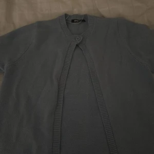 Ljusblå stickad kofta från Gina Tricot - Säljer en ljusblå stickad kofta från Gina Tricot. Koftan har lång ärm, rund halsringning och stängs med en knapp upptill. Perfekt att slänga över en topp för en enkel och stilren look.