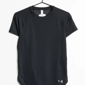 Svart träningst-shirt från Under Armour - Svart kortärmad träningst-shirt från Under Armour med rund hals och meshpaneler på ryggen för extra ventilation. Tillverkad i lätt och snabbtorkande tyg, perfekt för intensiva träningspass.  T-shirten har en något längre framsida och en liten logotyp nere på framsidan.