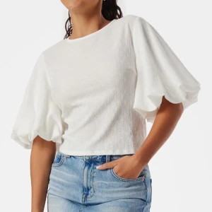 Vit blus med puffärmar - Säljer en vit blus med stora puffärmar och rund halsringning. Toppen har en croppad passform och är tillverkad i ett lätt material som passar perfekt till jeans eller kjol. 🩷