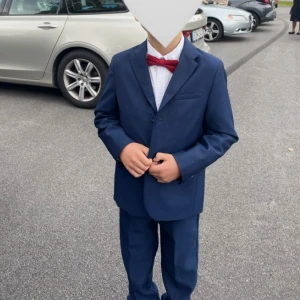 Mörkblå kostym för barn från Zara - Säljer en stilren mörkblå kostym för barn från Zara. Kostymen består av en kavaj med två knappar och matchande byxor, storlek 128. Perfekt för festliga tillfällen och studentfirande. Klassisk passform och snygg design med fickdetaljer. 