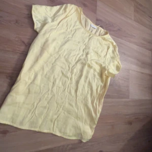 Gul kortärmad topp från Vila - Säljer en ljusgul kortärmad topp från Vila. Toppen har rund halsringning och är tillverkad i ett mjukt bomullsliknande material. Perfekt för varma dagar och enkel att matcha med olika outfits.