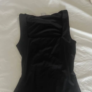 Svart linne - Säljer en svart, ärmlös topp med snygg fyrkantig ringning. Toppen har en tight passform och är tillverkad i ett mjukt, stretchigt material. Perfekt att styla till olika outfits! 