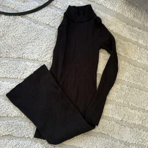 Svart ribbad klämning - Säljer en svart ribbad klänning med lång ärm. Klänningen har en hög krage och är i ett stretchigt material som sitter snyggt på kroppen. Storlek XXS men passar även som en M pga strechen.