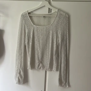 Vit spetsblus med lång ärm - Säljer en söt vit blus med lång ärm i spetsmaterial. Blusen har en fyrkantig ringning och är genombruten med ett vackert spetsmönster. Perfekt att styla med jeans eller kjol. Lite trådar som hänger från den men ä nog bara att klippa bort.