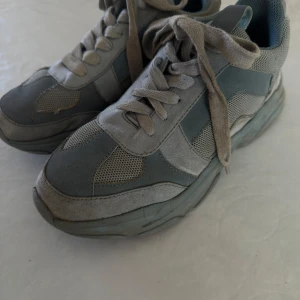 Blå sneakers med mesh och mockadetaljer - Säljer ett par blå sneakers med snygga paneler i mocka och mesh. Skorna har snörning och en platt sula som ger en sportig look. Perfekta för dig som gillar stilrena och bekväma skor till vardags.