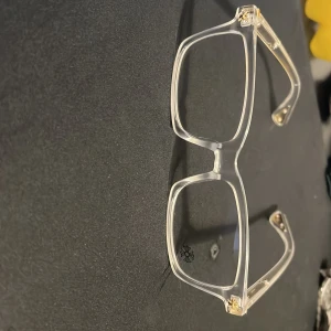 Transparenta glasögon med gulddetaljer - Stilrena glasögon med transparent båge och fyrkantig form. Skalmarna har snygga gulddetaljer som ger en exklusiv känsla. Perfekta för dig som vill ha en modern och trendig look.