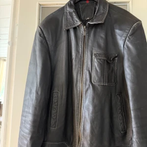 Vintage bikerjacka - Klassisk svart bikerjacka i okänt material. De har två hål på insidan, men inga defekter på utsidan (se de två sista bilderna). 