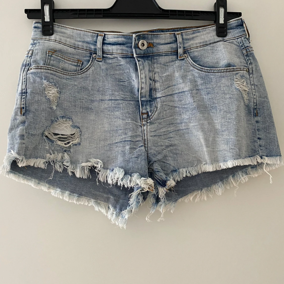 Ljusblå jeansshorts med slitningar och fransar