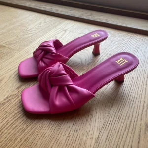 Rosa sandaler med knut från XIT - Säljer ett par trendiga rosa sandaler från XIT med fyrkantig tå och snygg knutdetalj framtill. Skorna har en låg klack och öppen tå. Skorna är i storlek 38 men skulle säga att dom även passar 39 då jag har storlek 39 i vanliga fall. Aldrig använda därför i väldigt bra skick! Perfekta nu inför sommaren då de har mycket färg!🩷🤍