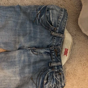 Blå bootcut jeansbyxor från DBC - Säljer ett par klassiska blå jeansbyxor från DBC. Byxorna är bootcut och har snygga detaljer med kontrastsömmar på fickorna. Perfekta för dig som gillar en tidlös jeansstil.