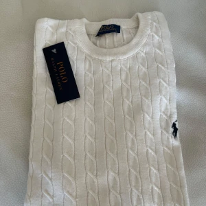 Vit tröja från polo ralphlauren - Säljer en klassisk vit kabelstickad tröja från Polo Ralph Lauren med rund halsringning och broderad logga på bröstet. Perfekt nu för sommaren☀️Hör av dig vid någon fråga💥pris kan diskuteras!