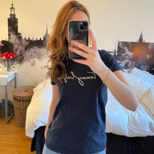 Mörkblå t-shirt Tommy Hilfiger - Mörkblå t-shirt från Tommy Hilfiger med vit logotyp i skrivstil på bröstet. Väl använd i storlek XS!!
