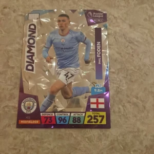 Phil Foden Diamond fotbollskort - Säljer ett glittrigt Diamond fotbollskort med Phil Foden från Manchester City. Kortet har lila och silver detaljer, spelarens namn, klubbmärke och engelska flaggan. Värden: Defence 73, Control 96, Attack 88, Total 257.