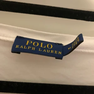 Vit långärmad från Polo Ralph Lauren - Säljer en klassisk vit långärmad från Polo Ralph Lauren med v-ringning och den ikoniska broderade loggan på bröstet. Perfekt basic-plagg i mjuk bomull som funkar till allt. Snygg och enkel stil!