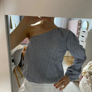 Svartvit rutig oneshoulder topp - Säljer en svartvit rutig oneshoulder topp. Storlek L men passar på mig som brukar ha XS/S