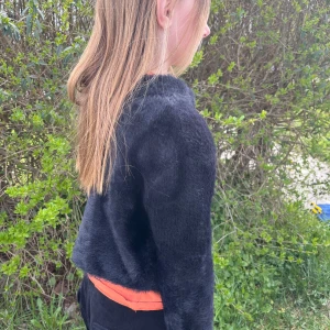 Svart pälsjacka i croppad modell - Säljer en svart, croppad pälsjacka med lång ärm. Jackan har en mjuk och fluffig känsla och är perfekt för att ge outfiten en extra touch. Enkel och stilren design utan synliga knappar eller dragkedja.