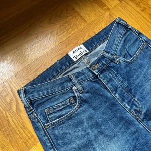 Blå jeans från Acne Studios - Säljer ett par klassiska blå jeans från Acne Studios i modellen Town Vintage. Jeansen har normal passform, raka ben och fem fickor. Perfekta för dig som gillar stilrena och tidlösa jeans med snygg tvätt.
