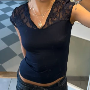 Mörkblå topp med spetsdetaljer - Snygg mörkblå topp med spetsdetaljer vid axlarna. Toppen har en tight passform och korta ärmar🩷🩷Pris kan diskuteras!