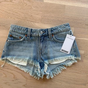 Blå jeansshorts med fransar från Weekday - Säljer ett par lågmidjade, blå jeansshorts från  weekday. Ej använda med lappen kvar, säljer då de inte passade. De är i Storlek 23 och slutsålda på hemsidan. Köparen står för frakt❤️.