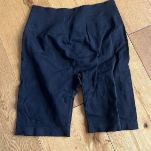 Svarta seamless träningsshorts Relode - Svarta seamless biker shorts från Relode med hög midja och diskret scrunch-detalj bak. Stretchigt material som sitter tight och följer kroppen, perfekt för gymmet eller andra sportaktiviteter. Relode-logga på linningen. Supersnygga och bekväma!