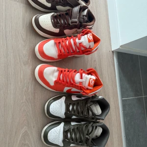Nike sneakers i olika färger och modeller - Tre par Nike sneakers: ett par Nike Air Force 1 i brunt och vitt med rutigt swoosh, ett par Nike Jordan 1 i vitt och rött med högt skaft och ett par Nike Dunk i vitt och olivgrönt. Alla har snörning och klassisk rund tå. Perfekta för dig som gillar streetstyle. Skorna längst åt höger är storlek 42,5 de andra 2 är storlek 43 500kr styck 