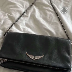 Svart axelväska med kedjerem - Snygg svart axelväska i skinn med silverfärgad kedjerem och dragkedja ifrån Zadig & Voltaire, fint skick. Nypris runt 4000