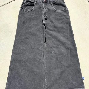 En av mina bästa JNCO-jeans Kom och besök mig, folkens 😎 - Säljer en svart lång jeanskjol från JNCO med bred passform och coolt broderat färgglatt motiv på bakfickan. Kjolen har klassiska jeansdetaljer som stora fickor, dragkedja och synliga kontrastsömmar. Perfekt för dig som gillar streetstyle och unik design.