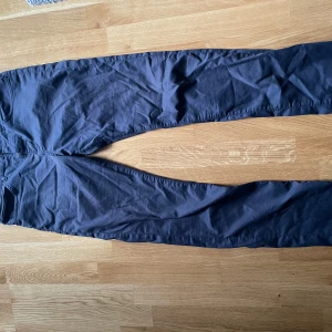 Mörkblå chinos från Hugo Boss 32/34 - Snygga mörkblå chinos från Hugo Boss i stretchigt bomullsmaterial. Klassisk rak passform med två bakfickor och diskreta detaljer. Perfekta för dig som vill ha en stilren och bekväm look.
