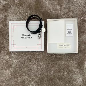 Alexander McQueen läderarmband med döskalle - Snyggt svart läderarmband från Alexander McQueen med silverfärgad döskalleberlock och spänne. Jätte bra skick. Nästintill oanvänd. 