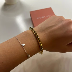 Guldigt armband med nitar från Edblad - Coolt armband från Edblad i guldton med spetsiga nitar runt hela bandet. Perfekt accessoar för att ge din outfit en edgy vibe. Stängs med smidig låsning och kommer i original ask. Orginalpris är 599, knappt använd. Skriv vid fler frågor🥰