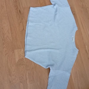 Ljusblå ribbad stickad tröja H&M - Supermysig ljusblå stickad tröja från H&M i ribbat material. Tröjan har en avslappnad passform med långa ärmar och rund halsringning. Perfekt för lager-på-lager och chill dagar. Enkel att matcha med jeans eller kjol.