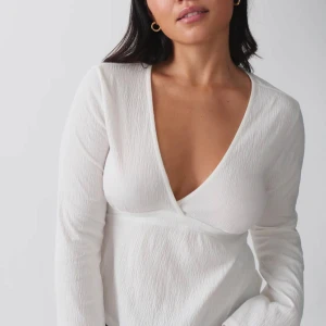 Vit omlottopp med v-ringning - Säljer en stilren vit omlottopp med djup v-ringning och lång ärm från gina tricot, passar perfekt både som vardagsplagg och även festplagg.Toppen har en lätt strukturerad yta och sitter snyggt figurnära. Perfekt för dig som gillar en clean och fräsch look. jag säljer denna för 200 original pris är 300 andvänds fåtal gånger o är i väldigt bra skick, hör av er om ni vill ha mer bilder på blusen så skickar jag de!