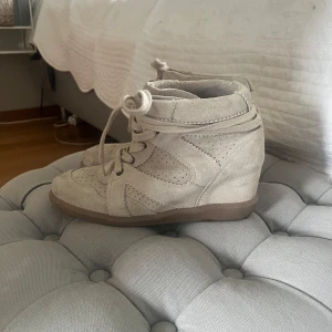 Pavement - Snygga beige sneakers i mocka med kilklack och snörning. Skorna har perforerade detaljer och en platt sula framtill. Perfekta för dig som vill ha en sportig look med lite extra höjd.