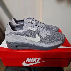 Oanvända Nike Air Max 90 Flyknit EU44.5 - Helt nya i original låda. Innermått 28.5 cm. Resellpris ca 2600 kr. Mitt sista pris 1600kr Lätta skor med stickad överdel som andas bra. Skickar spårbart och försäkrat. OBS! Inga byten eller returer. Skambud undanbedes! 