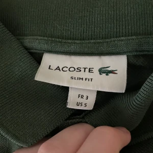 Mörkgrön Lacoste piké - Snygg mörkgrön pikétröja från Lacoste i slim fit-modell. Klassisk krage, korta ärmar och knappar framtill. Storlek S men sitter som en Xs. 200kr om man hämtar upp i Malmö! Nypris är 1000-1300