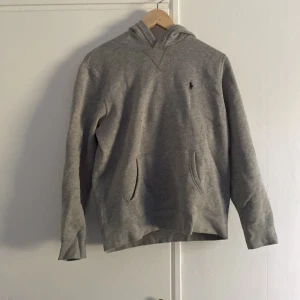 Grå hoodie från Polo Ralph Lauren - Säljer en klassisk grå hoodie från Polo Ralph Lauren med broderad logga på bröstet. Tröjan har huva, känguruficka hör av er vid intresse