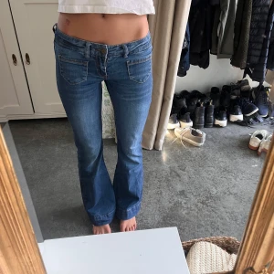 Blå bootcut jeans  - Snygga blå jeans med bootcut-modell och låg midja. Klassisk femficksdesign och i mjukt jeanstyg som sitter skönt. Perfekta för dig som gillar en retro vibe och vill ha ett par jeans som sticker ut lite extra.