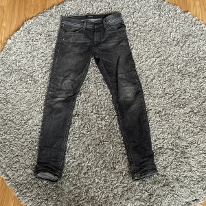 Replay jeans - Säljer ett par svart/grå replay jeans i storlek 150. Jeansen sitter ganska tajt på benen och passar  någon som är ca 160cm. De understa stygnen på lappen där bak har lossnat så den hänger ut lite som du kan se på bild 3. Men om du har ett skärp så går det bra. Annars så har den inga defekter direkt och är hyfsat bra skick. Hör av dig vid funderingar. Pris kan diskuteras.