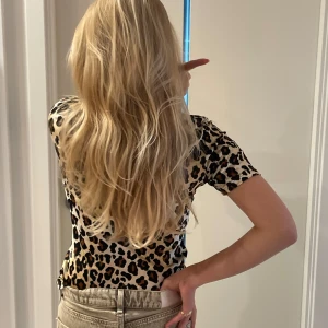 Leopardmönstrad t-shirt med hög krage - Snygg t-shirt med leopardmönster från märket KOOKAI. Modellen  har korta ärmar och en lite högre krage. Materialet känns mjukt och stretchigt lite som sammet. Den är i xs men passar mig i S